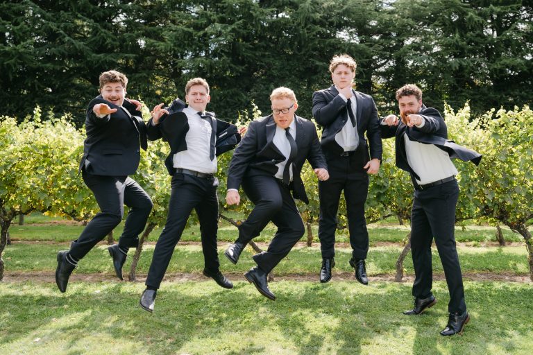 Groomsmen jumping for joy in Wedding vineyard