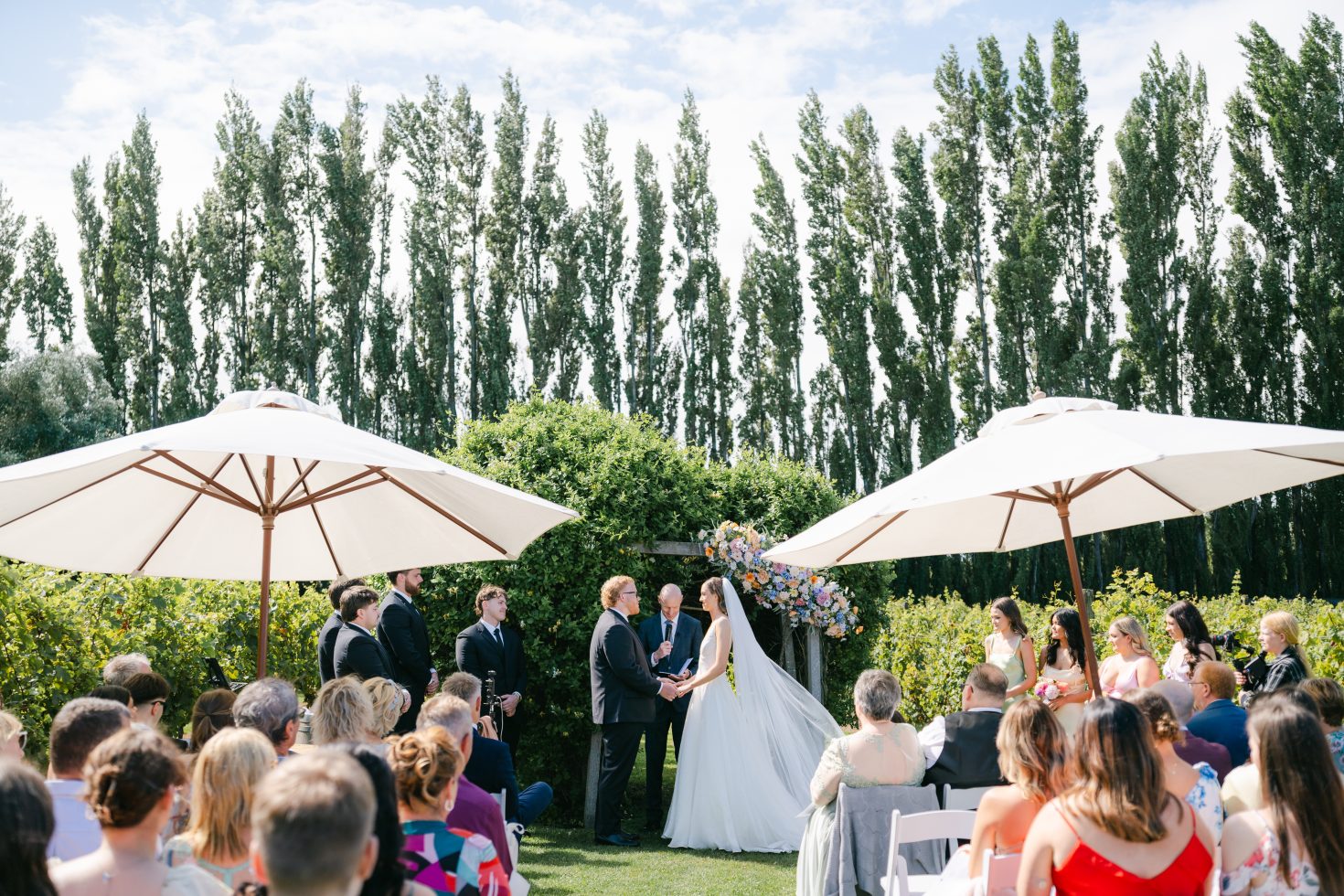Outdoor wedding ceremony setup with white umbrellas and tall poplar trees at Cossars Wineshed.
