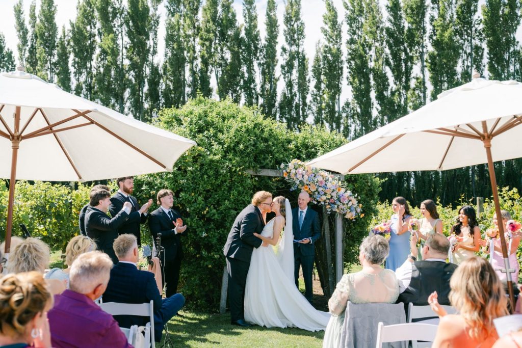 Bride and groom sharing a kiss at the altar during a garden ceremony in Canterbury.