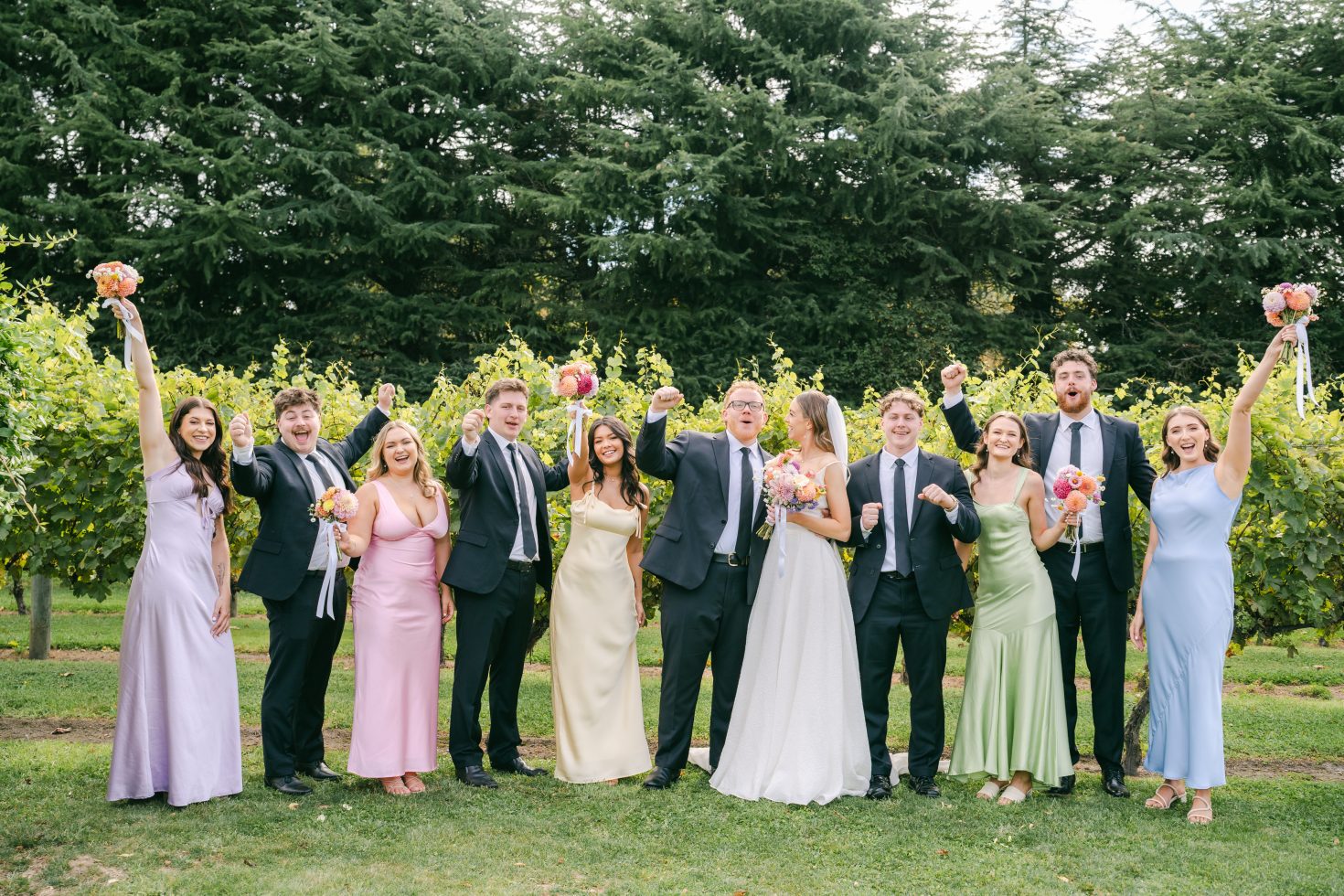 A large bridal party laughing together outside at a Cossars Wineshed wedding.