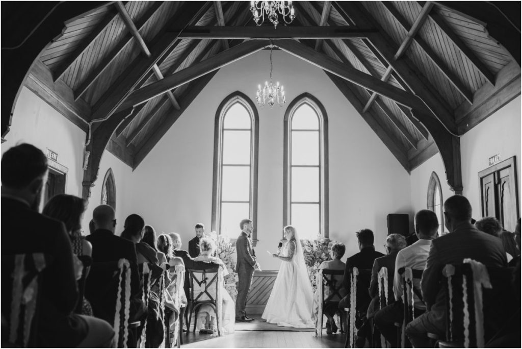 Black and white wedding photography: Wide architectural shot of a wedding ceremony inside the Kingsdown Manor chapel.