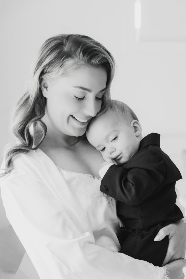 Black and white family portrait: Soft, loving close-up of a mother hugging her baby boy during preparation by Agnes Grace Photo & Film.