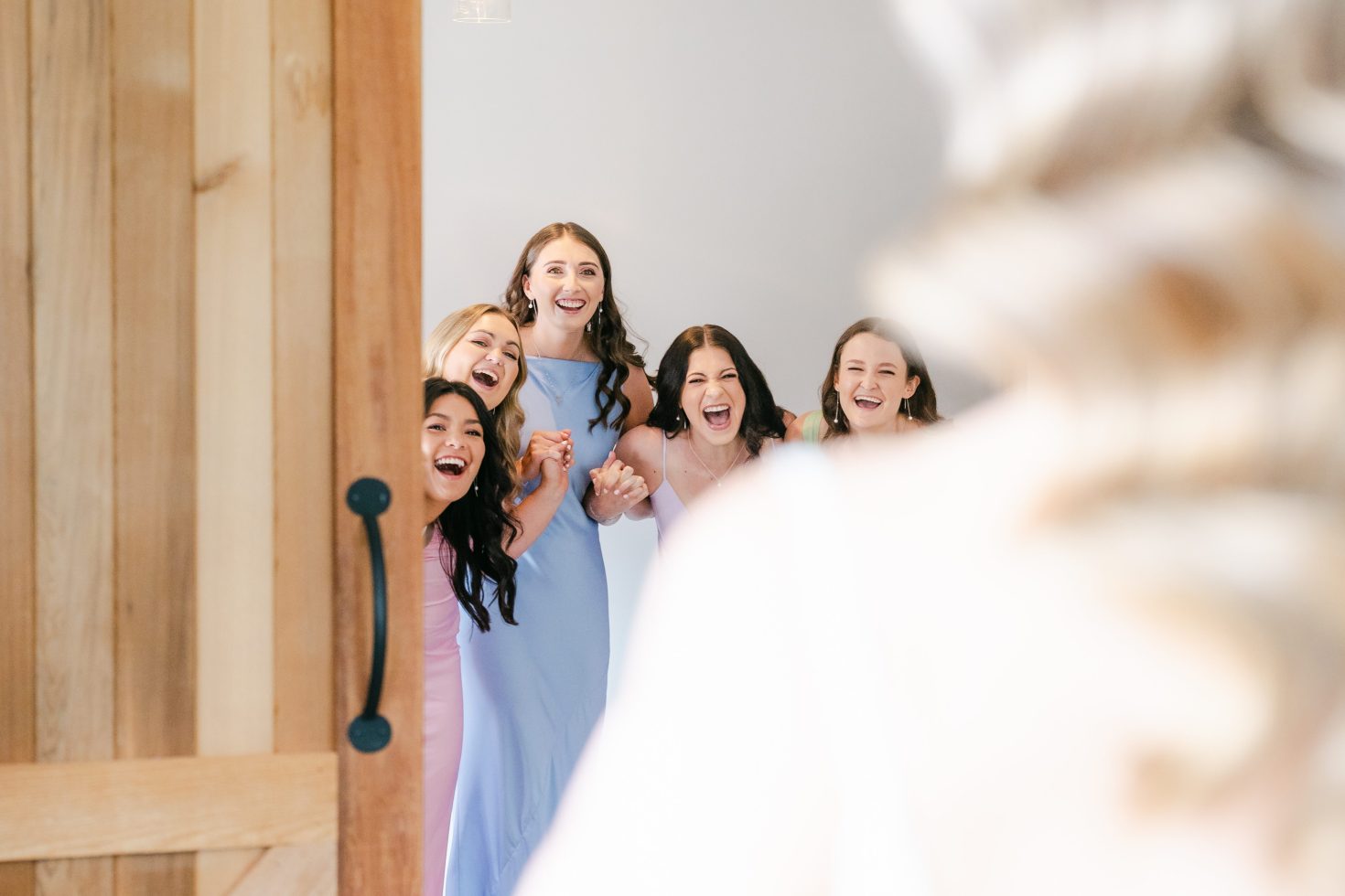 Candid bridesmaid first look: Bridesmaids cheering and laughing as they see the bride in her gown for the first time.