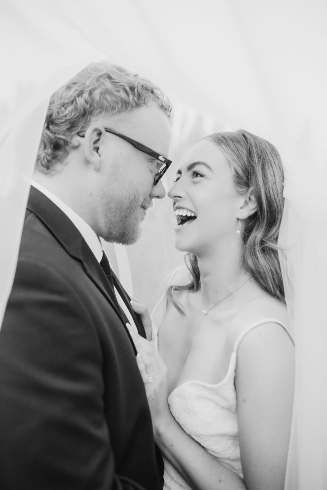 Romantic close-up profile of Blair and Ben laughing under a wedding veil. Cossars Wineshed Wedding