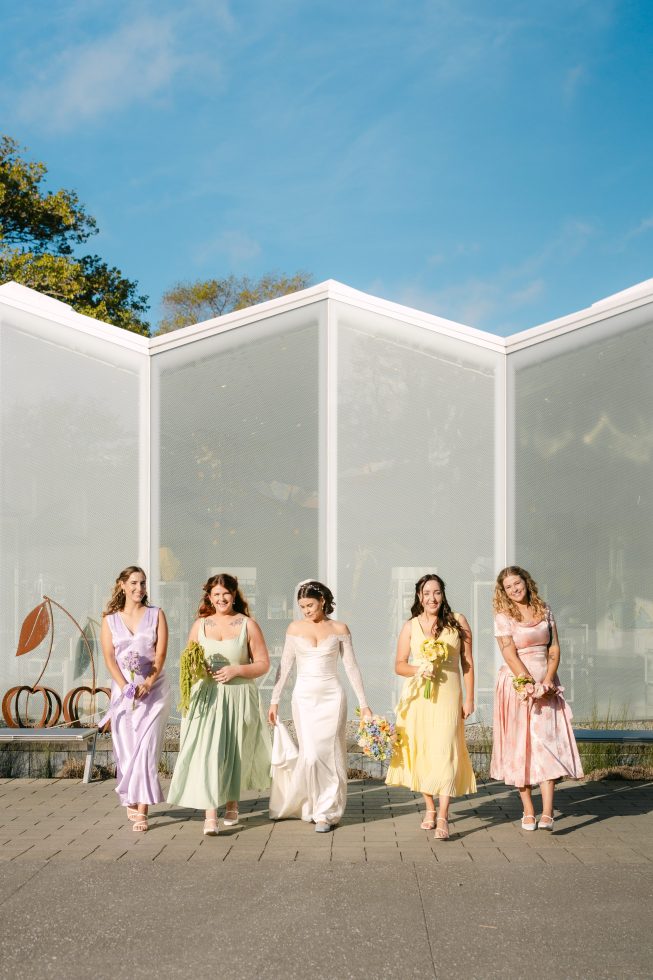Modern wedding reception design: Bridesmaids and family standing outside a contemporary white geometric marquee tent.