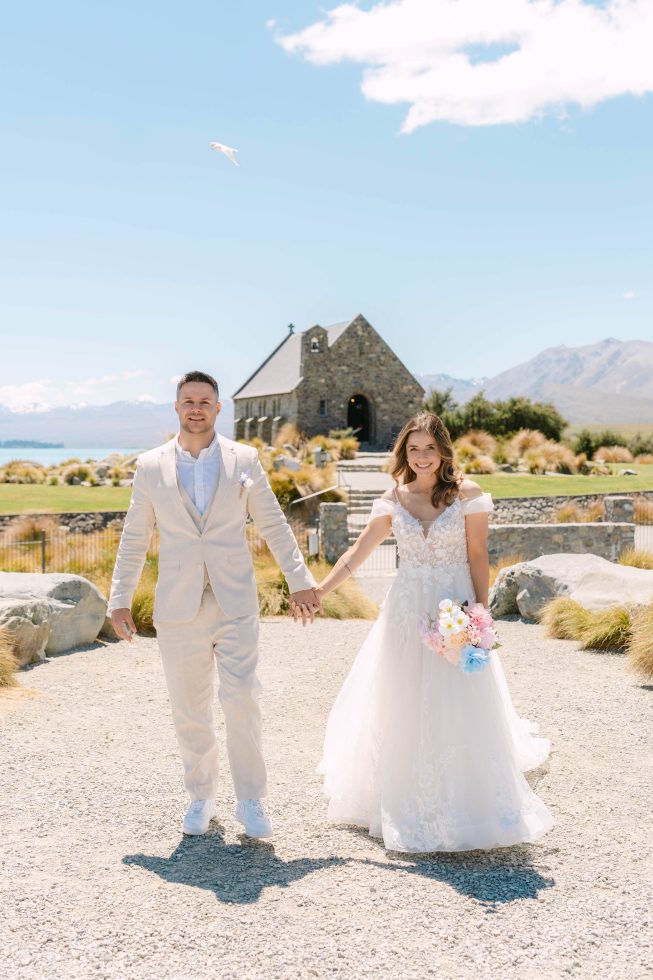 A newly married couple holding hands outside the chapel during a private Tekapo Church of the Good Shepherd wedding session.