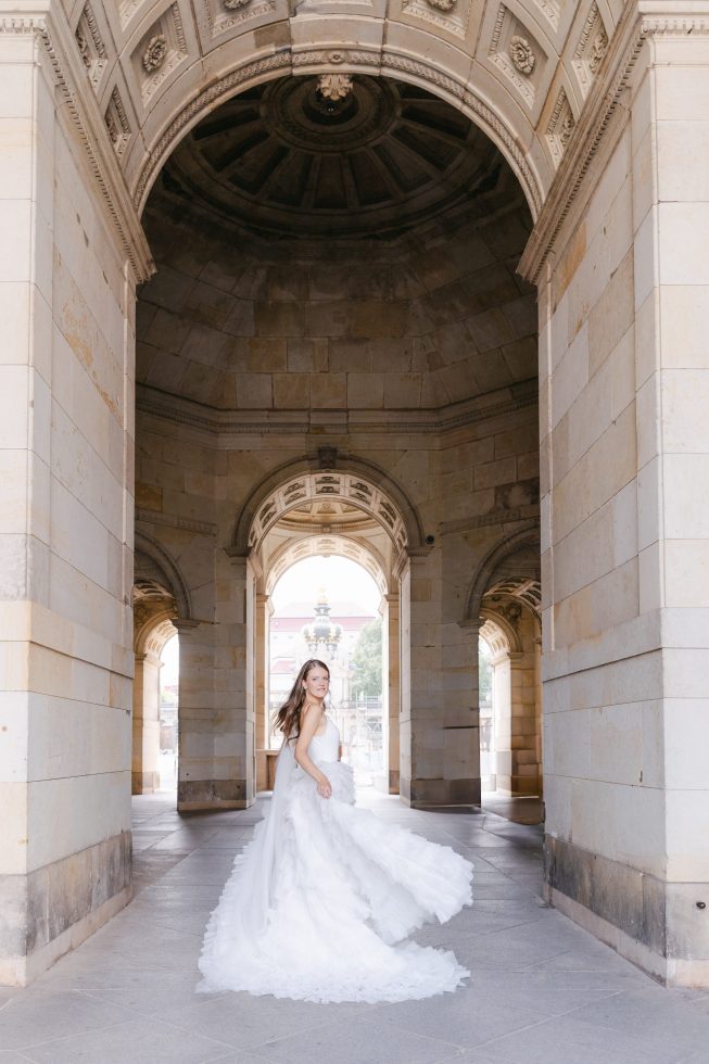 Fine art wedding photography: Bride standing within a deep, dramatic stone archway entry in Europe.