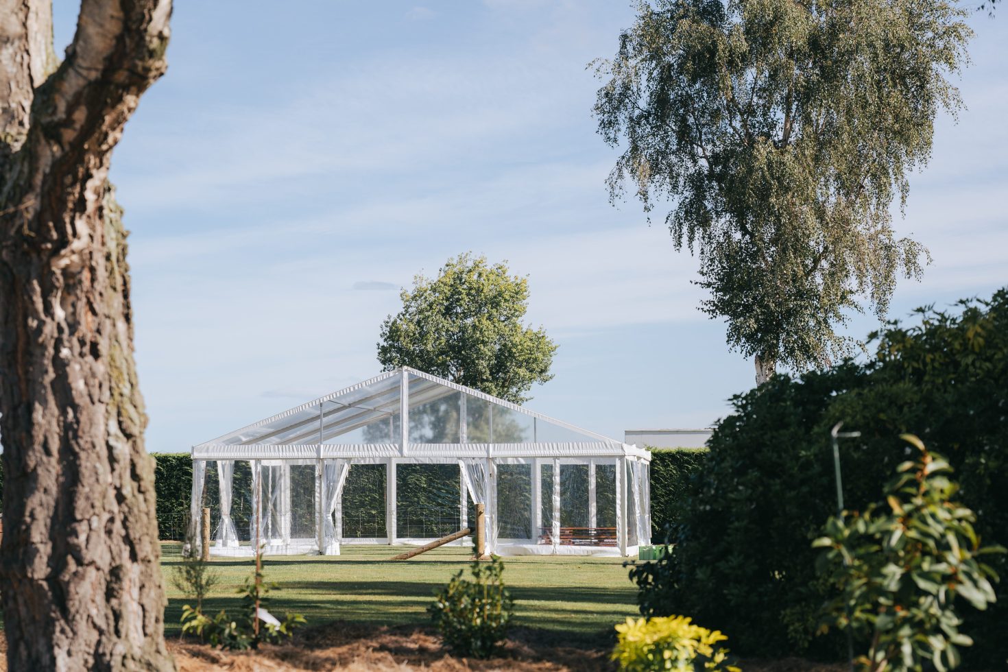 Wide landscape shot of a fully installed clear marquee wedding venue on a private lawn