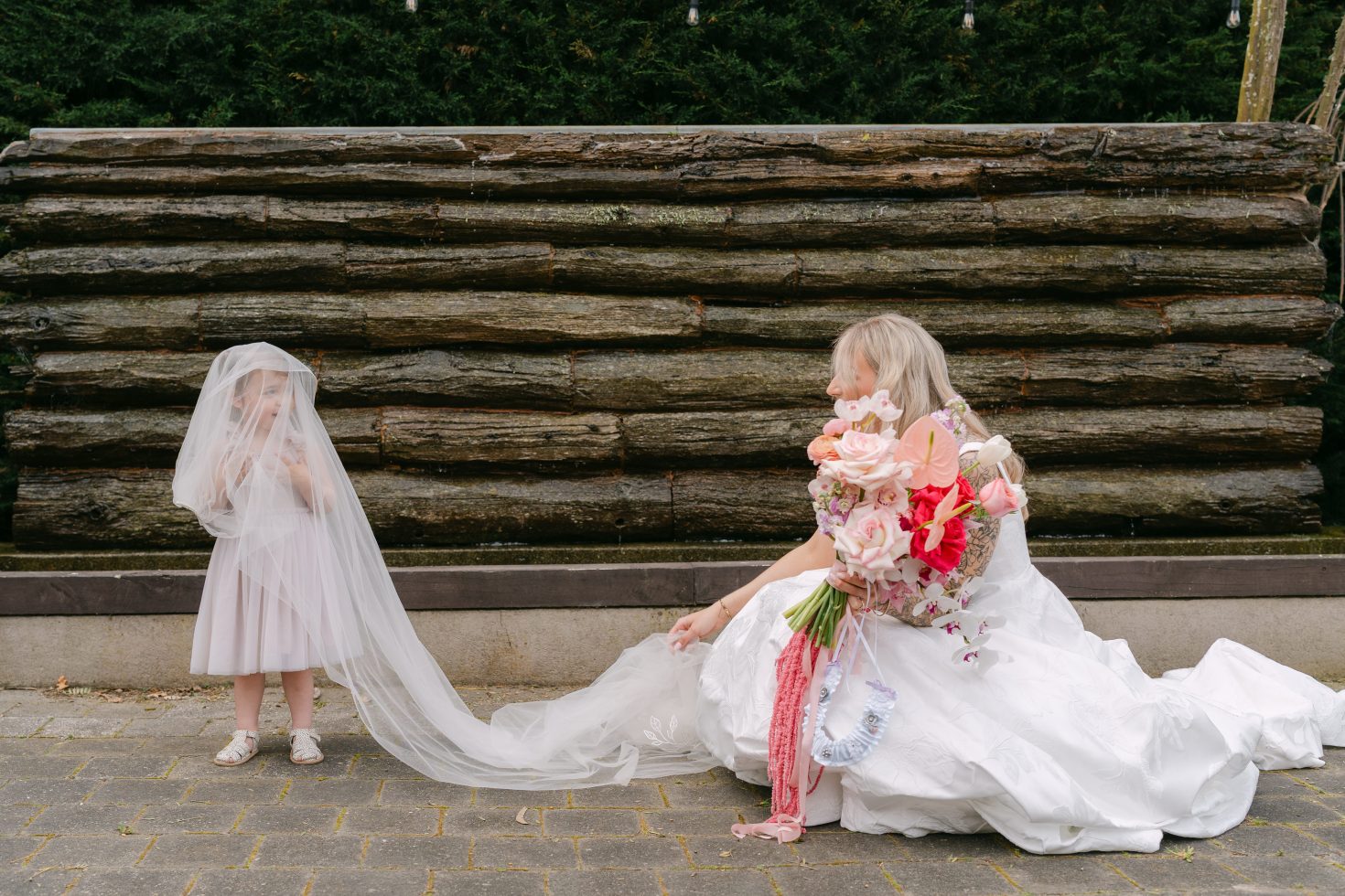 Bride sitting outside on stone steps showing off a long cathedral wedding veil
