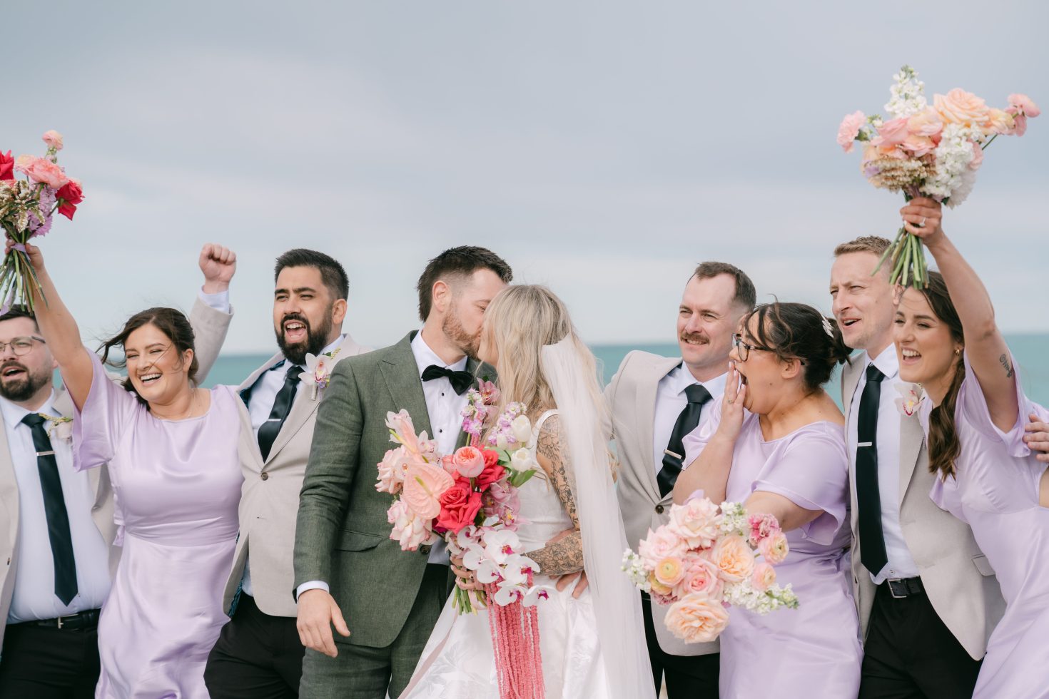 Steph and Peter kissing with their bridal party celebrating at Kingsdown Manor