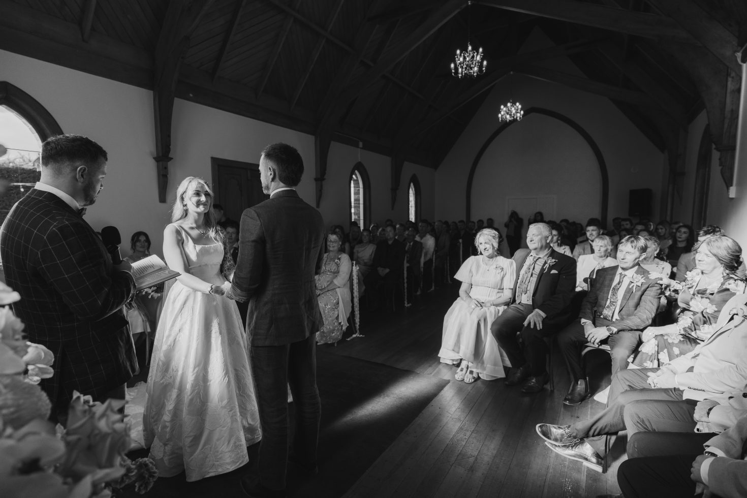 Dramatic ceremony lighting inside Kingsdown Manor chapel during wedding vows