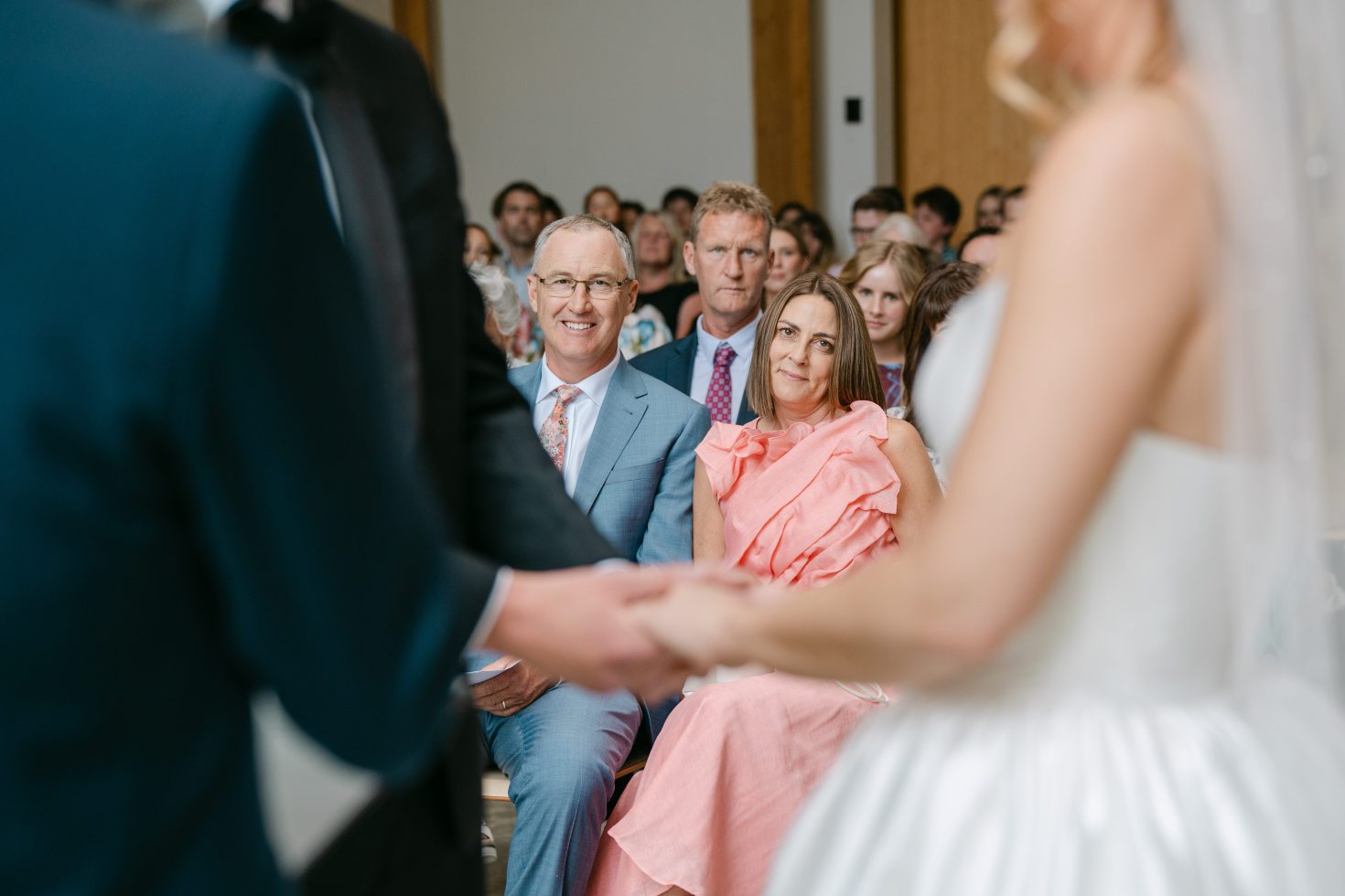Close-up shot over the groom's shoulder of Annabelle smiling during their wedding ceremony.