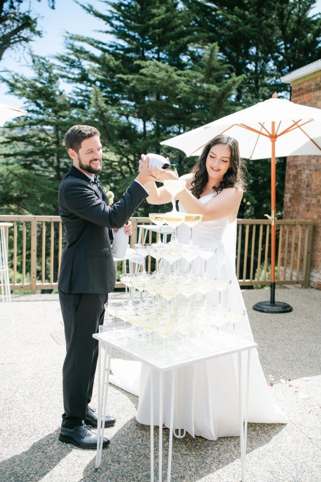 Bride and groom champagne spraying celebration outside on the reception deck