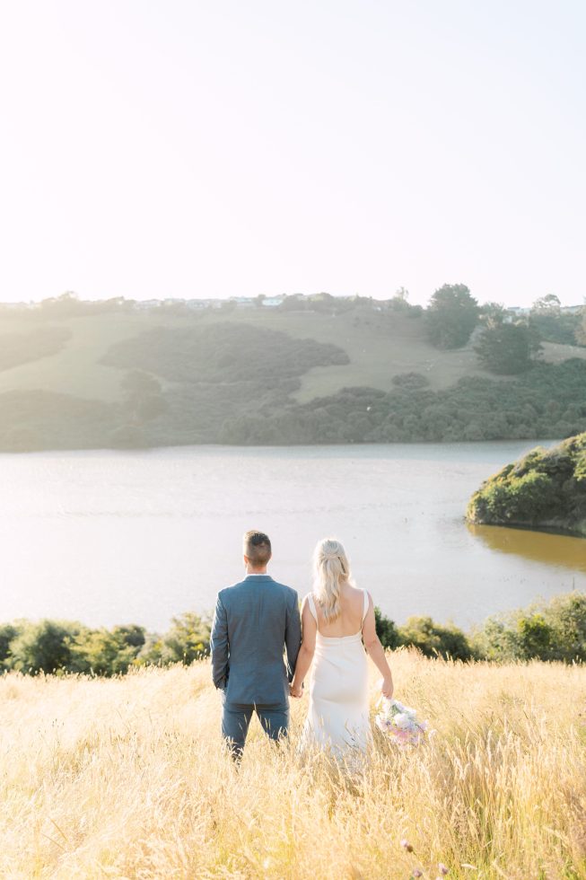 Sun drenched golden hour couple portrait strolling by a scenic lagoon edge