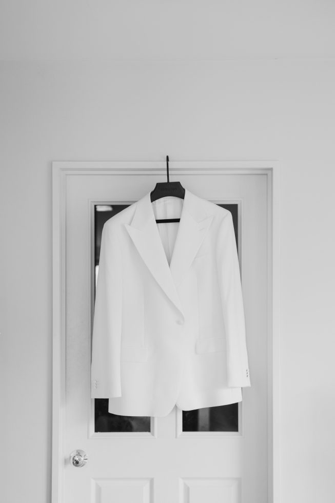 A white suit hanging in groom's getting ready space in Christchurch, New Zealand
